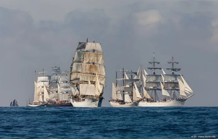 Tres veleros tradicionales con velas blancas navegando juntos en el océano azul durante las Tall Ships Races en Burdeos.
