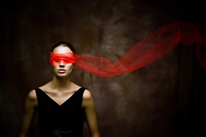 Mujer con los ojos vendados con tela roja ondeante, vestida de negro sobre fondo oscuro, evocando la ópera La Novia del Zar de Burdeos