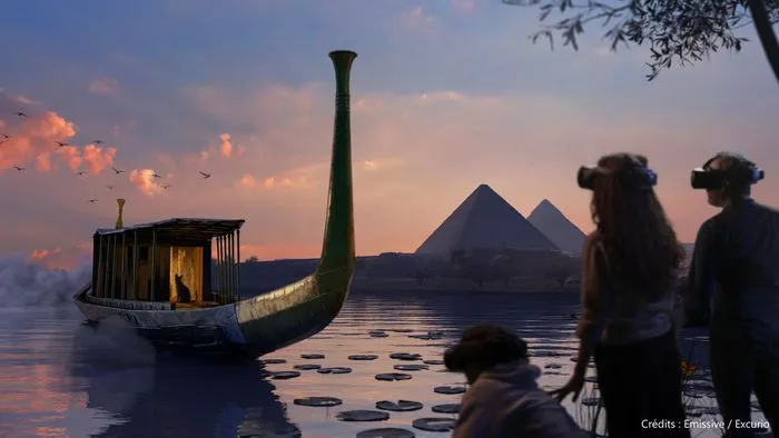 Vista inmersiva de una exposición que muestra una barca egipcia estilizada en el agua, pirámides al fondo y visitantes observando la escena al atardecer.