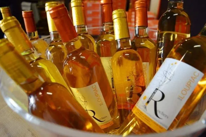 Colección de botellas de vino blanco Loupiac con tonos dorados y ámbar durante una cata en Burdeos