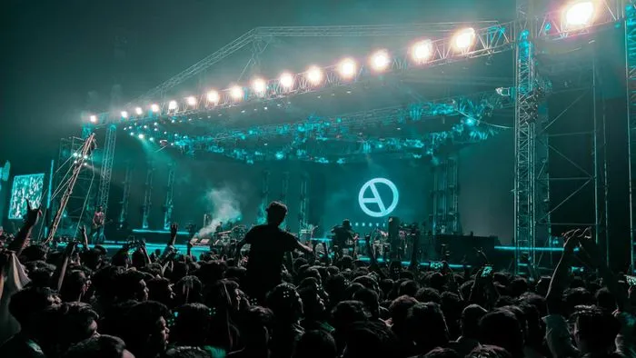 Multitud de espectadores frente a un escenario iluminado en el festival Isulia en Burdeos, con iluminación azul turquesa en la base submarina.