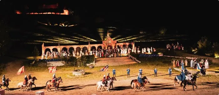 Espectáculo nocturno de la Batalla de Castillon en Burdeos con jinetes a caballo, público de fondo y estructuras arquitectónicas iluminadas
