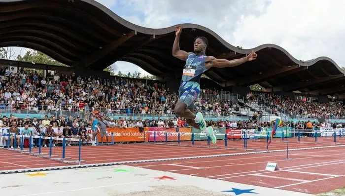 Atleta saltando una valla durante el Décastar, competición internacional de atletismo en Burdeos, ante un estadio lleno de espectadores.
