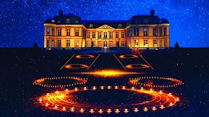 Un castillo iluminado en amarillo dorado que domina patrones geométricos creados por velas encendidas bajo un cielo nocturno estrellado.