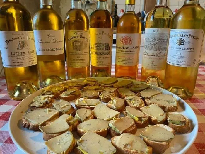 Plato de foie gras sobre tostadas rodeado de siete botellas de vinos blancos y rosados de Burdeos, durante una cata en las puertas abiertas del castillo de Sainte-Croix-du-Mont.