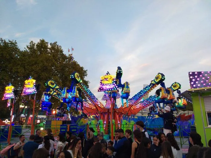 Atracción de feria iluminada con elefantes coloridos decorados con miles de luces LED en la feria de otoño de Burdeos, con visitantes en primer plano.