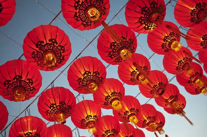 Linternas rojas chinas iluminadas colgando en el cielo azul, decoraciones para la celebración del Año Nuevo Chino en Burdeos