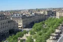 Vista aérea de las Allées de Tourny en Burdeos con edificios de estilo haussmanniano, árboles verdes y fachadas de piedra.