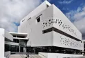 Fachada blanca moderna del Museo del Mar de Burdeos con perforaciones circulares, escaleras de acceso y cielo azul de fondo