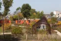 Vista del Parque aux Angéliques en Burdeos con pérgola de madera, vegetación otoñal colorida, valla blanca en primer plano y el río Garona al fondo