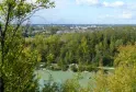 Vista panorámica del Parque de la Ermita de Santa Catalina en Burdeos con un lago en primer plano, bosque de álamos y la ciudad al fondo bajo un cielo nublado