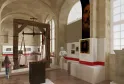 Interior del Museo Nacional de Aduanas de Burdeos que presenta una exposición con una balanza histórica de madera, paneles informativos con bandas rojas, retratos y objetos aduaneros en una galería abovedada.