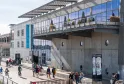Fachada moderna de Cap Sciences en Burdeos con grandes ventanales, terraza ajardinada y plaza pública concurrida con visitantes y ciclistas
