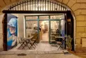 Fachada de la tienda de vinos Levain Le Vin en Burdeos, con terraza exterior equipada con sillas plegables, vitrinas iluminadas y cartel promocional azul